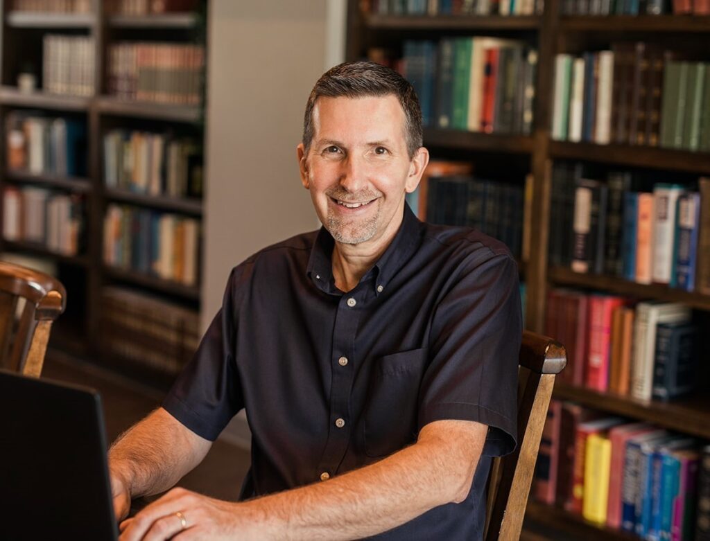 Mike Panfil, owner of Zeta Bookkeeping, at his desk in a library setting